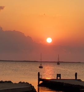 a sailboat is docked at a pier with the sun setting at Bayside Inn Key Largo in Key Largo