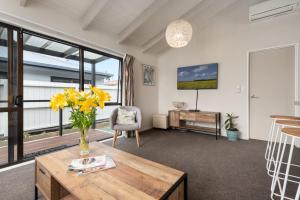 a living room with a vase of flowers on a table at The Mount Beach Pad - Mt Maunganui Holiday Home in Matapihi