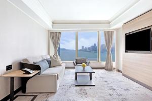 a living room with a couch and a large window at Harbour Grand Kowloon in Hong Kong