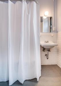 a white shower curtain in a bathroom with a sink at Leo House in New York