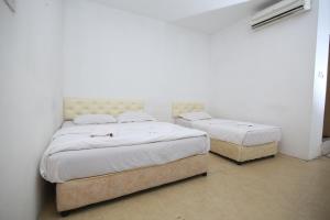 two beds in a bedroom with white walls at L&C Premium Stay in Kuching