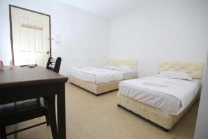 2 camas en una habitación con mesa y escritorio en L&C Premium Stay, en Kuching