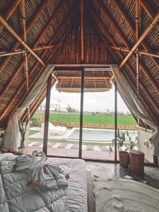 a bedroom with a bed and a large window at Capila Villa Bali in Canggu