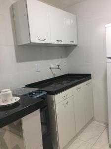 Una cocina con gabinetes blancos y una encimera negra. en Hospedagem da Rose - Cabo Frio, en Cabo Frío 3 fotos más
