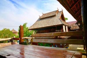 a building with a roof with a wooden fence at Baan Lanna Resort in Chon Buri