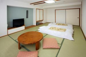 a room with two beds and a table and a tv at Yumeoi-so in Aso