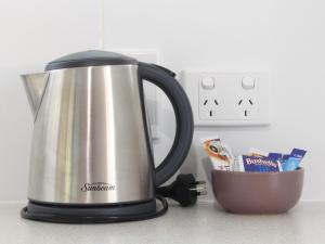 a tea kettle sitting on a counter next to a cup at Huntsville Caravan Park in Maryborough