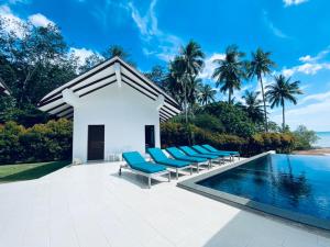 a villa with a swimming pool and blue lounge chairs at Krabi Beach House, SHA Extra Plus in Ao Nam Mao