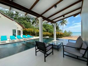 an outdoor patio with a table and chairs and a swimming pool at Krabi Beach House, SHA Extra Plus in Ao Nam Mao