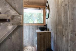 a small bathroom with a window and a mirror at Castlemaine Gardens Luxury Safari Tents in Castlemaine