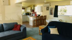 a living room with two couches and a kitchen at Country Cottage Rotorua in Whakatahuri