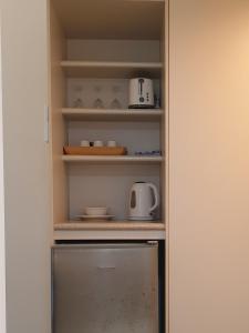a pantry with a shelf with dishes and appliances at Rainforest Castaways Resort and Spa in Mission Beach