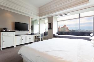 a bedroom with a white bed and a flat screen tv at The Riverside Hotel in Seoul