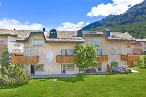 a large apartment building with a yard with grass at Abitaziun Sur Sass - Silvaplana Surlej in Surlej