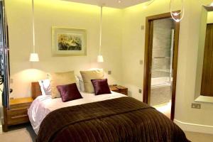 a bedroom with a large bed with purple pillows at Stylish large cool 3 bed 3 bath Marylebone +AC in London