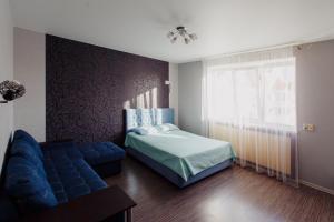 a bedroom with a bed and a blue couch at Liproom Apartments on Smorodina in Lipetsk