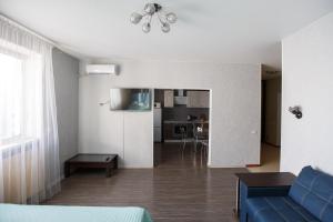 a living room with a blue couch and a kitchen at Liproom Apartments on Smorodina in Lipetsk