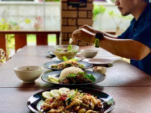 a person sitting at a table with plates of food at Beck's Resort in Haad Pleayleam