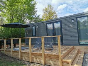 a tiny house with a deck with an umbrella at Am See 90 in Seekirchen am Wallersee