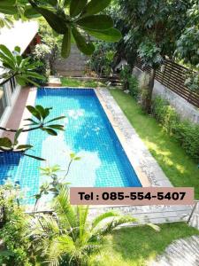 a swimming pool in a garden with a sign on it at Nature Home in Phra Nakhon Si Ayutthaya