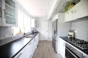 a kitchen with white cabinets and black counter tops at 2mins to lakefront Family Retreat in Taupo