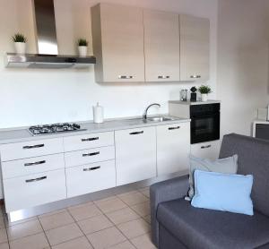 a kitchen with white cabinets and a sink and a couch at ROSE E TULIPANI 2 - VICINO OSPEDALE NEGRAR in Negrar +9 photos