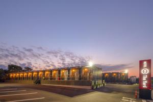 a building with lights in a parking lot at night at HOTEL R9 The Yard Isumi in Chōjamachi