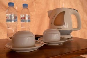 vKirirom Pine Resort في Chambok: غلاية الشاي والأكواب على طاولة مع زجاجات المياه