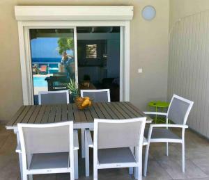 une table en bois avec des chaises blanches et une table avec un ananas. dans l'établissement V2 Dream panorama of the ocean, à Oyster Pond