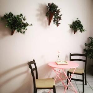 uma mesa rosa e cadeiras numa sala com plantas em I capricci dell'Etna 2 di Puglisi em Mascalucia
