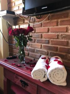 a table with a vase of roses and towels at Pousada Cabanas da Serra Lumiar in Lumiar