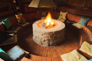 a large fire pit in a room with chairs at Valamanzi Lodge in Nyati Wilderness in Vaalwater