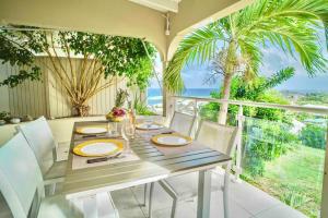a dining table with white chairs and a view of the ocean at V4 Magical view of the ocean and Saint Barth in Oyster Pond
