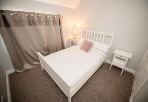 a small bedroom with a white bed with a pink pillow at Breathing Space in Fort William