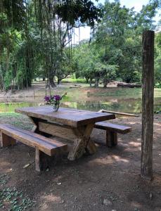 een houten picknicktafel met een vaas met bloemen erop bij Vivenda dos Guaranys - uma imersão na natureza - Loft in Conservatória