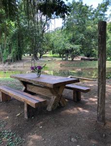 einen hölzernen Picknicktisch mit einer Vase Blumen darauf in der Unterkunft Vivenda dos Guaranys - uma imersão na natureza - Loft in Conservatória