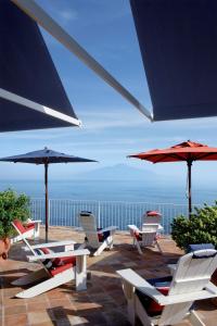 索倫托的住宿－梅森米納維塔酒店，庭院里摆放着一组椅子和遮阳伞