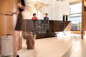 a woman standing in front of a mirror in a lobby at Hotel Maison FL in Paris