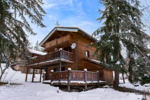 a log cabin in the snow with a balcony at Chalet Côté Cœur, La Tania, with Outdoor Hot Tub and 7 Ensuite Rooms in La Tania