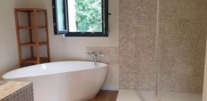 a white bath tub in a bathroom with a window at Clairseine in Tournedos-sur-Seine