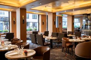 a restaurant with tables and chairs and windows at Hotel Maison FL in Paris