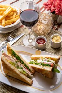 a sandwich and french fries on a plate with a glass of wine at Hotel Maison FL in Paris