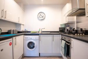 cocina con lavadora y reloj en la pared en No11 Nursery Covent, en Mansfield