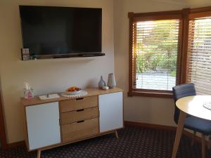 a living room with a dresser with a television on the wall at Above the River Karapiro Bed & Breakfast in Karapiro