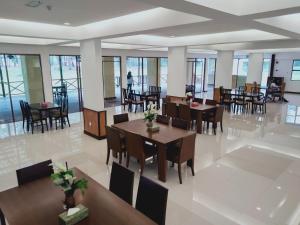 a dining room with tables and chairs and windows at TEMU PRIMULA in Kampong Seberang Timor