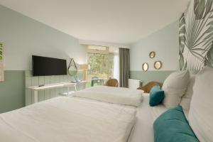 een hotelkamer met 2 bedden en een televisie bij Hotel Bispinger Heide by Center Parcs in Bispingen