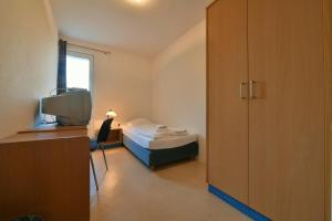 a small bedroom with a bed and a television at SKYBASIC Merseburg in Merseburg