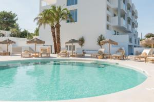 a swimming pool with chairs and a building at The Olive Boutique Suites & Spa in Cala Llonga