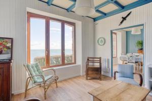 een woonkamer met een tafel en uitzicht op de oceaan bij Villa des Roches - vue mer exceptionnelle in Clohars-Carnoët