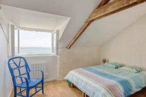 ein Schlafzimmer mit einem Bett und einem blauen Stuhl in der Unterkunft Villa des Roches - vue mer exceptionnelle in Clohars-Carnoët